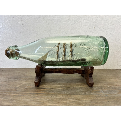 593 - A vintage handmade ship in glass bottle on hardwood stand