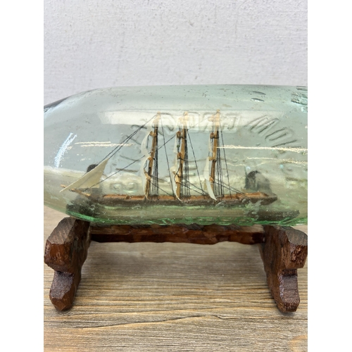 593 - A vintage handmade ship in glass bottle on hardwood stand