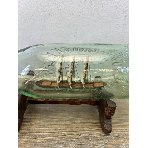 593 - A vintage handmade ship in glass bottle on hardwood stand