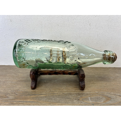 593 - A vintage handmade ship in glass bottle on hardwood stand