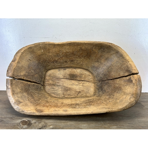 597 - A 19th century carved elm dough bowl - approx. 16cm high x 66cm long x 40cm wide