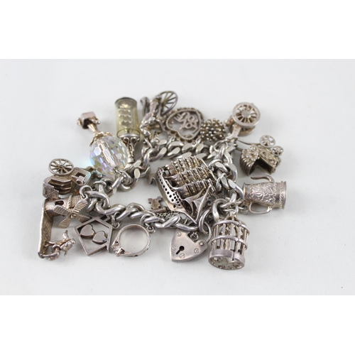 2390 - A silver charm bracelet with assorted charms - approx. gross weight 97g