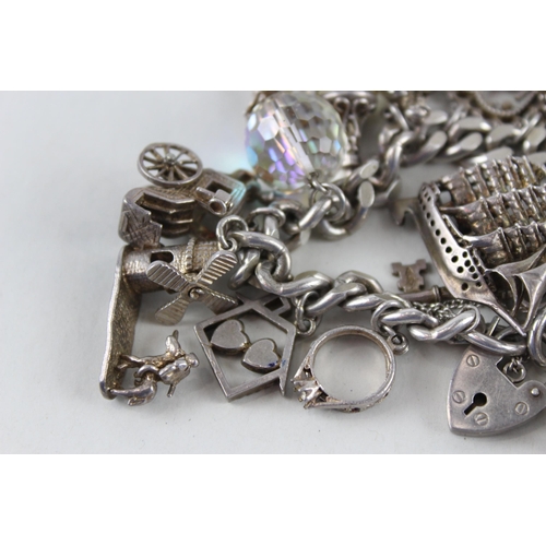 2390 - A silver charm bracelet with assorted charms - approx. gross weight 97g