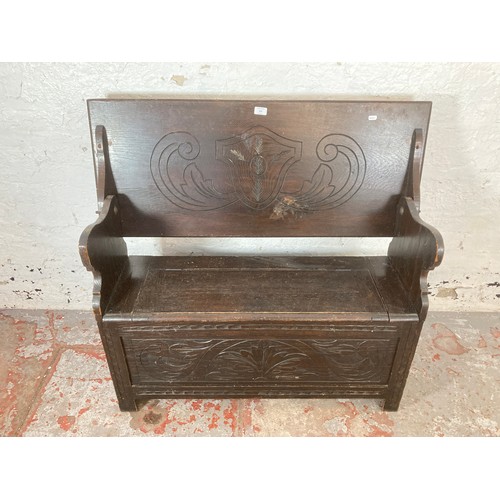 208 - A carved oak monk's bench - approx. 97cm high x 107cm wide x 32cm deep