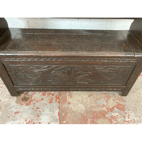 208 - A carved oak monk's bench - approx. 97cm high x 107cm wide x 32cm deep