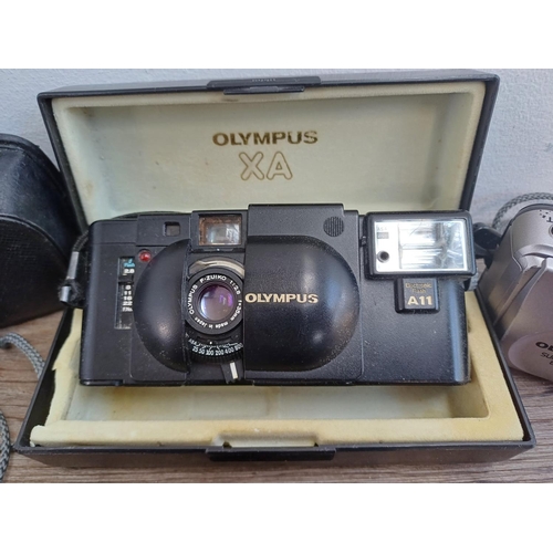 323 - Four Olympus compact 35mm cameras, one cased XA fitted with A11 flash, one µ[mju:]-II Zoom 115, one ... 