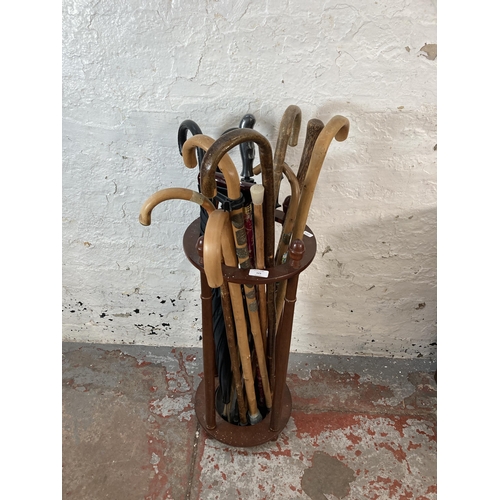 123 - A mahogany circular stick stand containing walking sticks and umbrellas - approx. 71cm high x 30cm d... 