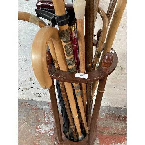 123 - A mahogany circular stick stand containing walking sticks and umbrellas - approx. 71cm high x 30cm d... 