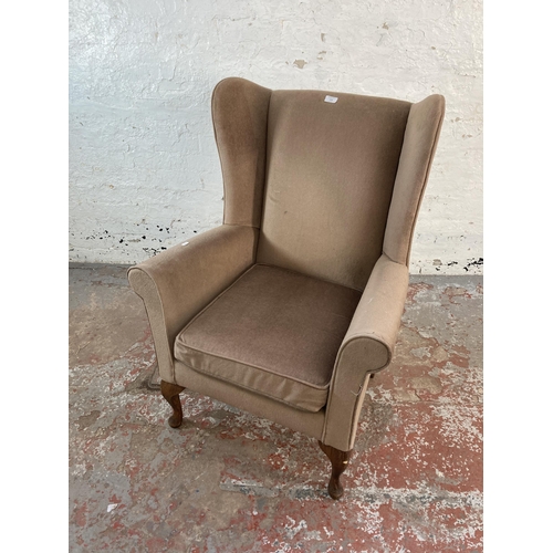 128 - A late 20th century brown fabric upholstered wingback armchair on cabriole supports