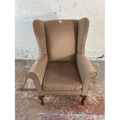 128 - A late 20th century brown fabric upholstered wingback armchair on cabriole supports