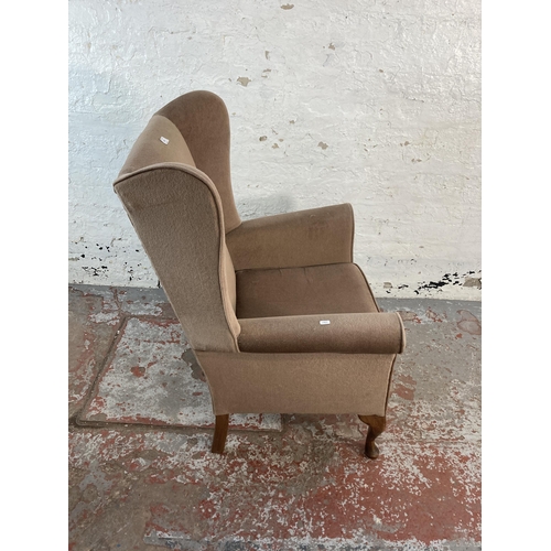 128 - A late 20th century brown fabric upholstered wingback armchair on cabriole supports