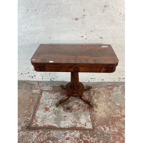 137 - A 19th century flame mahogany fold over games table with green baize interior and brass lions paw su... 