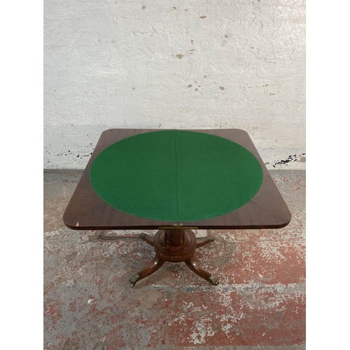 137 - A 19th century flame mahogany fold over games table with green baize interior and brass lions paw su... 