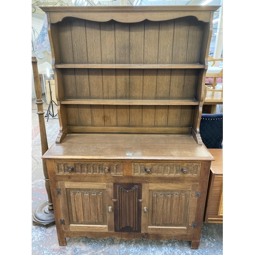 145 - An L. Marcus Ltd. carved oak linenfold dresser - approx. 184cm high x 121cm wide x 48cm deep