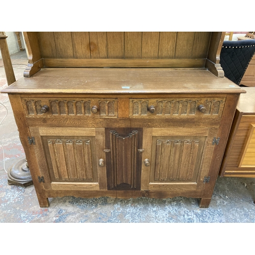 145 - An L. Marcus Ltd. carved oak linenfold dresser - approx. 184cm high x 121cm wide x 48cm deep