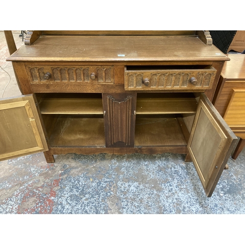 145 - An L. Marcus Ltd. carved oak linenfold dresser - approx. 184cm high x 121cm wide x 48cm deep