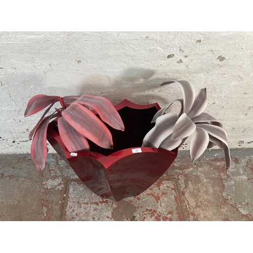 168 - A modern red fibreglass planter with two artificial plants - approx. 61cm high