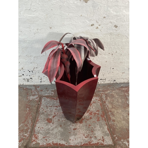 168 - A modern red fibreglass planter with two artificial plants - approx. 61cm high