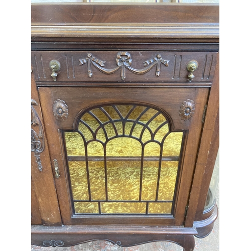 25 - An Edwardian carved mahogany sideboard with two glazed doors and yellow fabric lined interior - appr... 