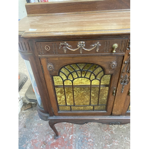 25 - An Edwardian carved mahogany sideboard with two glazed doors and yellow fabric lined interior - appr... 