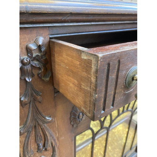 25 - An Edwardian carved mahogany sideboard with two glazed doors and yellow fabric lined interior - appr... 