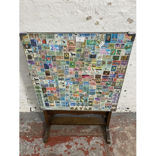 37 - A mid 20th century oak tilt top occasional table with worldwide stamp design top - approx. 76cm high... 