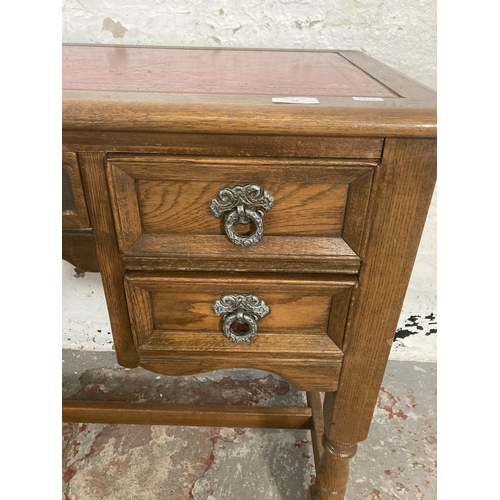 56 - A carved oak writing desk with red leather insert - approx. 73cm high x 107cm wide x 47cm deep