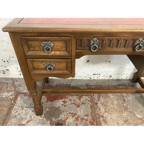 56 - A carved oak writing desk with red leather insert - approx. 73cm high x 107cm wide x 47cm deep