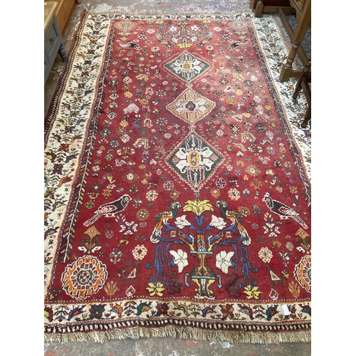 61 - A 20th century red floral pattern rug - approx. 270cm x 180cm