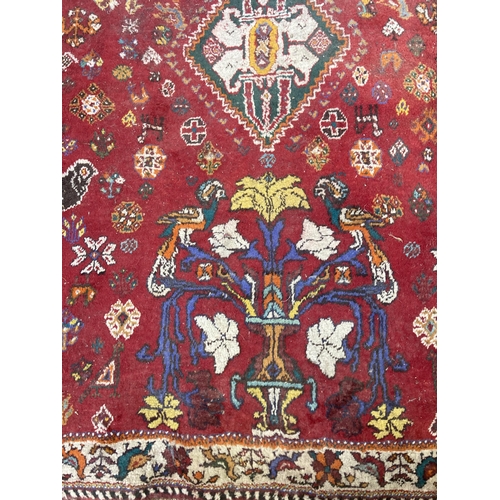 61 - A 20th century red floral pattern rug - approx. 270cm x 180cm