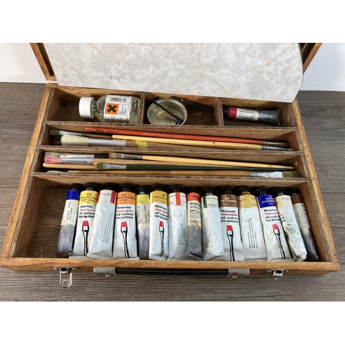 1110A - A mid 20th century plywood artist's travel case containing a collection of oil paints and brushes