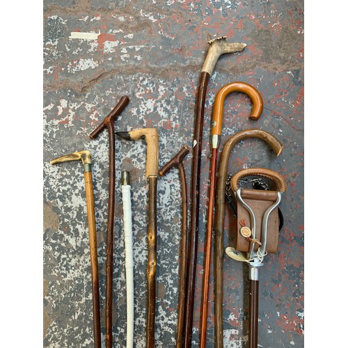 1097 - A collection of vintage walking sticks and canes together with a vintage aluminium and leather shoot... 