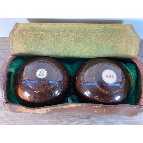 1141 - A pair of early 20th century brown leather cased Taylor Rolf & Co Ltd. Lignum Vitae crown green bowl... 