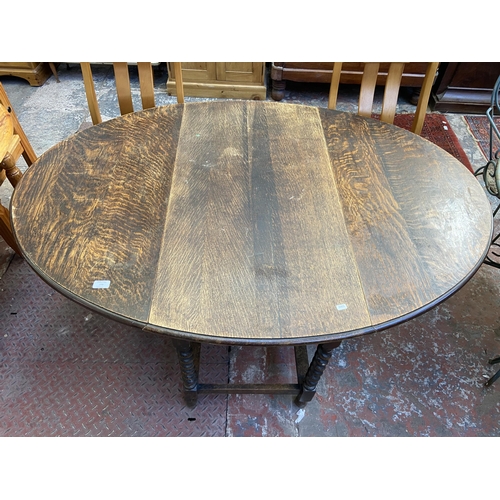 100 - An early 20th century oak drop leaf gate leg oval dining table on barley twist supports - approx. 73... 