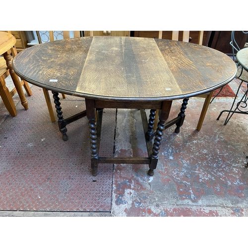 100 - An early 20th century oak drop leaf gate leg oval dining table on barley twist supports - approx. 73... 