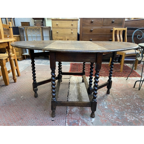 100 - An early 20th century oak drop leaf gate leg oval dining table on barley twist supports - approx. 73... 