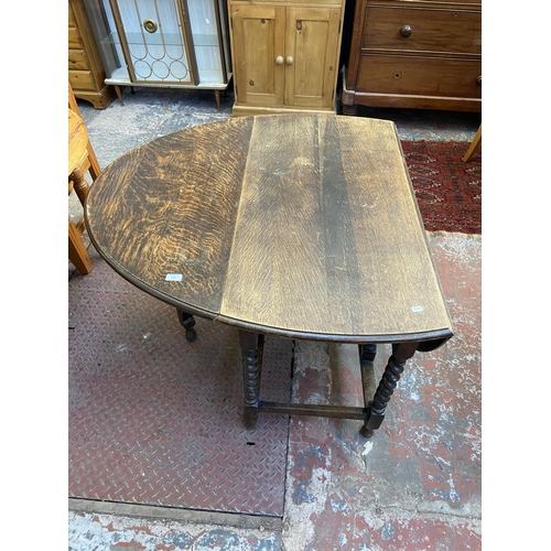 100 - An early 20th century oak drop leaf gate leg oval dining table on barley twist supports - approx. 73... 