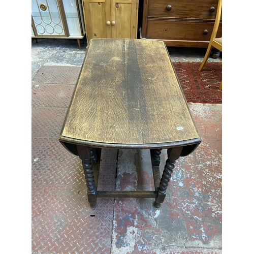 100 - An early 20th century oak drop leaf gate leg oval dining table on barley twist supports - approx. 73... 