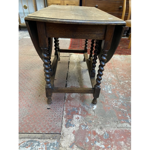 100 - An early 20th century oak drop leaf gate leg oval dining table on barley twist supports - approx. 73... 