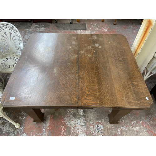 120 - An Arts & Crafts oak wind out dining table on castors - approx. 73cm high x 104cm wide x 124cm long