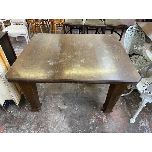 120 - An Arts & Crafts oak wind out dining table on castors - approx. 73cm high x 104cm wide x 124cm long