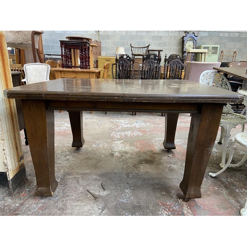 120 - An Arts & Crafts oak wind out dining table on castors - approx. 73cm high x 104cm wide x 124cm long