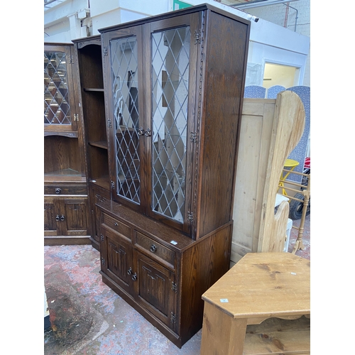 134 - A Jaycee carved oak display cabinet with two upper leaded glass doors and two lower linenfold cupboa... 