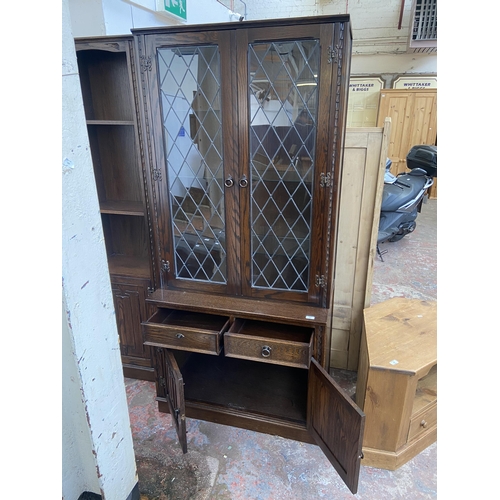 134 - A Jaycee carved oak display cabinet with two upper leaded glass doors and two lower linenfold cupboa... 