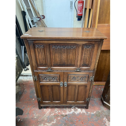 137 - An Old Charm carved oak linenfold cocktail cabinet - approx. 110cm high x 76cm wide x 28cm deep