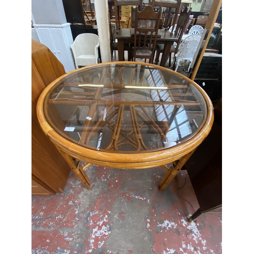 175 - A mid/late 20th century wicker and cane circular dining table with smoked glass top - approx. 78cm h... 