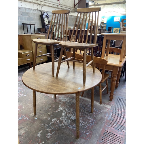 94 - A mid 20th century Dinette teak effect and beech circular drop leaf dining table and two Ercol style... 