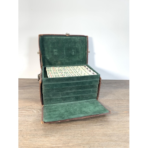 409 - An early 20th century leather cased bone and bamboo complete Mahjong set