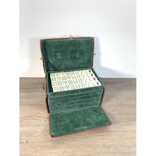 409 - An early 20th century leather cased bone and bamboo complete Mahjong set