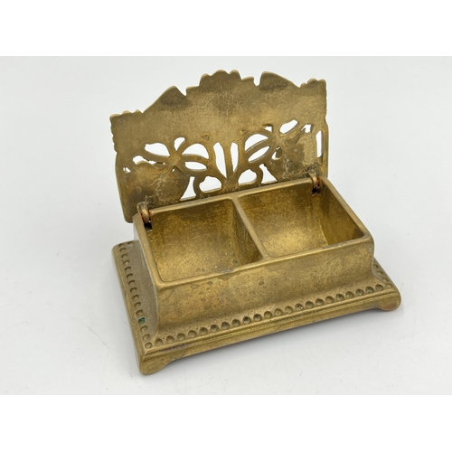 2114 - Two items, one Art Nouveau brass lidded stamp holder and one silver plated four slice toast rack